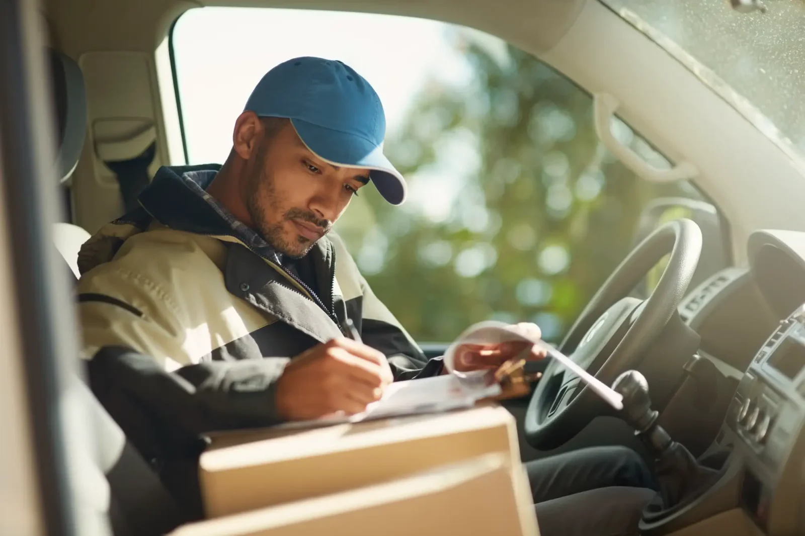 Delivery driver writing on a clipboard on top of a box.
