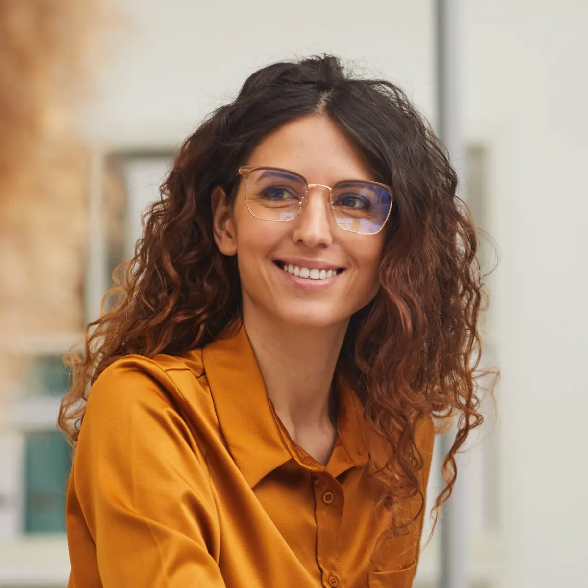 Young professional woman with glasses sitting at a computer smiling at a colleague.